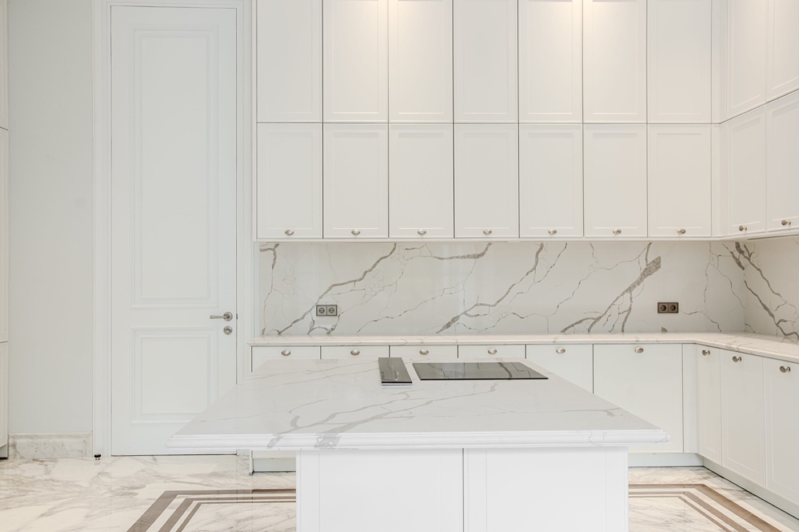 White kitchen with a quartz island and a veined quartz backsplash