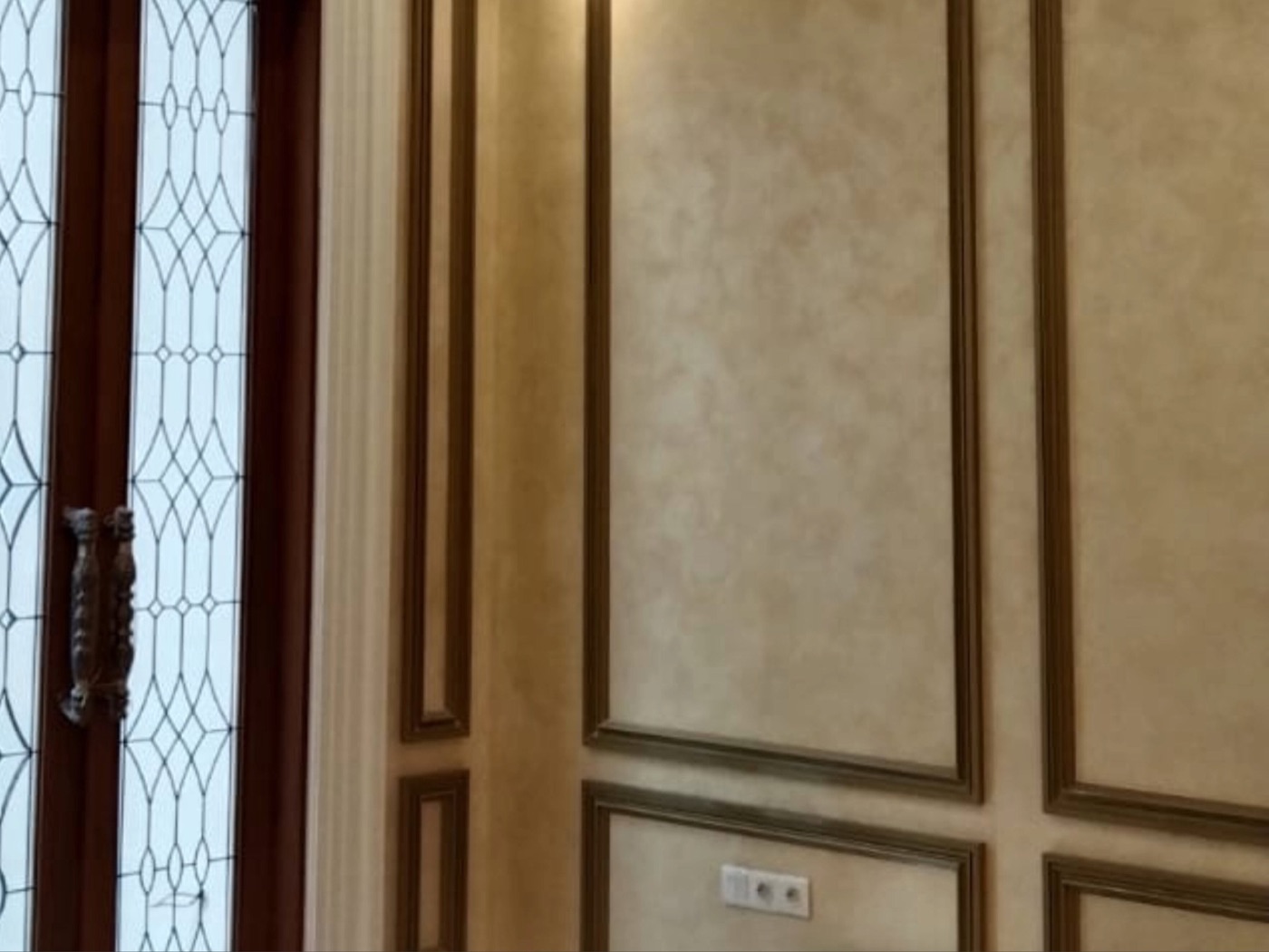 Wall with a soft, mottled painted finish, panelled frames and a door with stained glass
